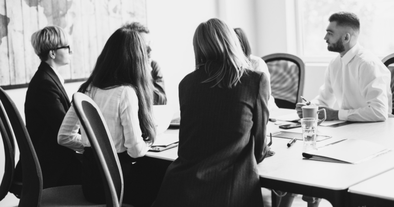 Réunion en salle, quatre personnes autour d'une table de travail - Unsplash