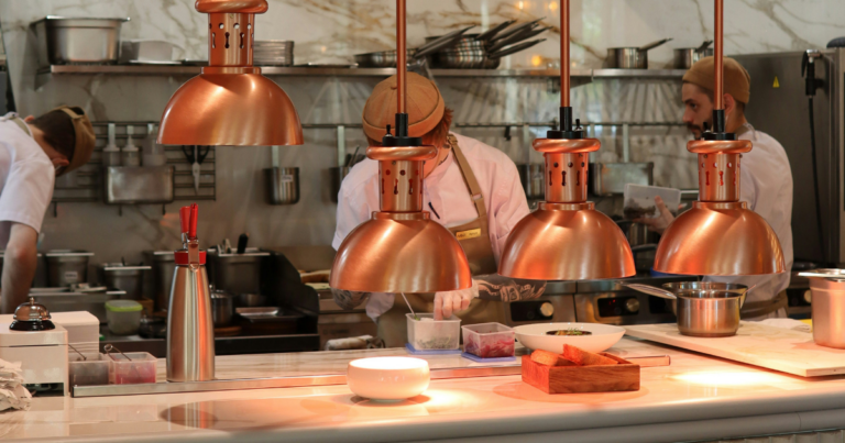 Cuisine ouverte avec suspensions en cuivre, équipe en plein service - Unsplash