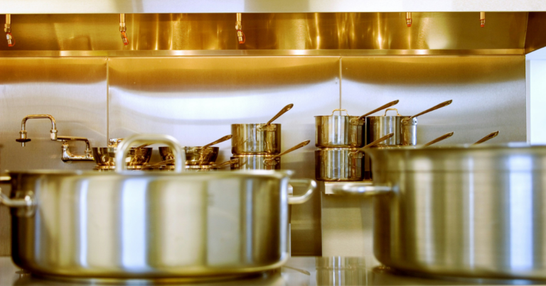 Casseroles et marmites en cuivre suspendues au-dessus d'un plan de travail - Unsplash