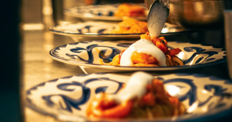 Ligne d'assiettes en cours de dressage, sauce versée à la cuillère, cuisine en pleine activité - Unsplash